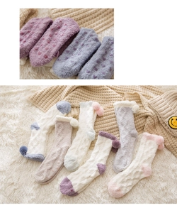 Detail of coral fleece socks with anti-slip heart grips and plush ball decoration