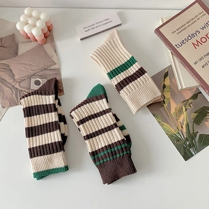 Flat lay of striped crew socks in cream, brown, and green with a ribbed knit texture