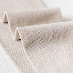 Detailed macro view of beige knitted fabric texture showing premium stitching quality
