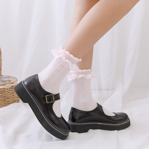 Détail de chaussettes blanches à volants avec tricot rose et chaussures Mary Jane noires