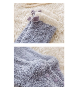 Detail of coral fleece socks featuring velvet bow and heart anti-slip rubber grips