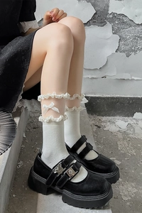 Détail de chaussettes blanches à volants avec nœud et chaussures Mary Jane noires