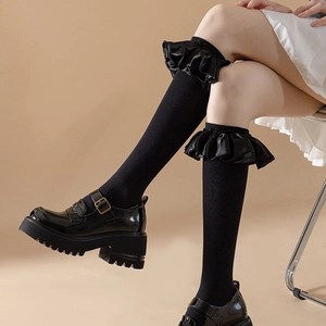 Detail of black Lolita knee-high socks with ruffled lace trim and Mary Jane shoes