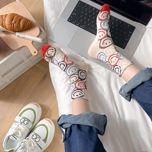 Detail of crew cotton socks with colorful smiley faces next to sneakers and laptop