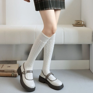 Detail of white cable knit knee-high socks paired with vintage mary jane shoes