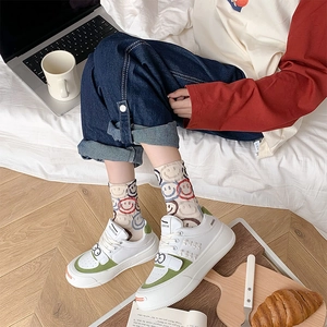 Close-up of stylish smiley face crew socks paired with white and green chunky sneakers