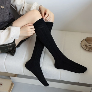 Detail of black cable knit knee-high socks with vintage diamond texture on leg