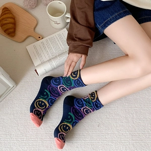 Detail view of colorful knitted crew socks with smiley face patterns and pink toe accents