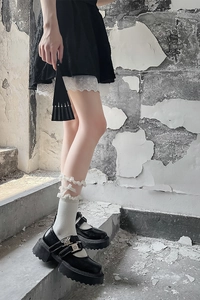 Détail de chaussettes à volants avec nœud et chaussures Mary Jane noires à plateforme