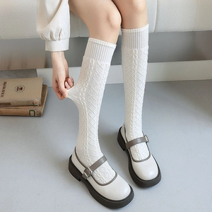 Detail of white cable knit knee-high socks showing high elasticity and soft texture