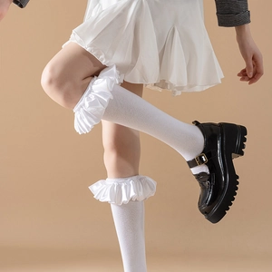 Close-up of white Lolita calf-length socks with ruffled satin lace and Mary Jane shoes
