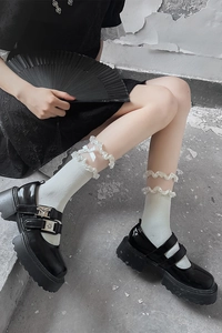 Détail de chaussures Mary Jane noires vernies avec chaussettes blanches à volants et nœud