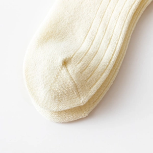 Detailed close-up of cream knit socks showing fine toe stitching and ribbed texture