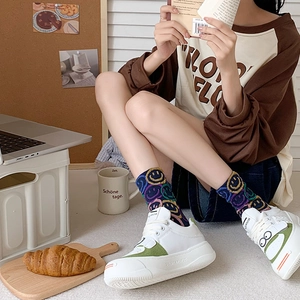 Detail of white sneakers with green accents and colorful smiley face crew socks