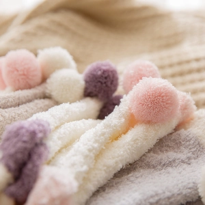Thick coral fleece socks with fluffy pom-poms in pastel colors for winter warmth
