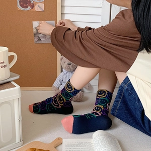 Close-up of crew socks with colorful graffiti smiley faces and pink contrast toe details