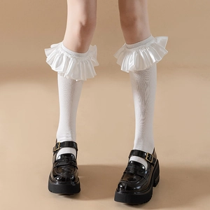 Close-up of white Lolita socks featuring large satin ruffles with black Mary Jane shoes