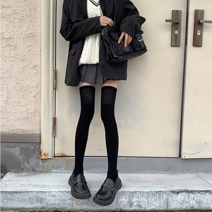 Détail de chaussettes hautes noires avec bords côtelés dans une tenue de style JK