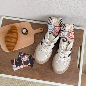 Flat lay of cream sneakers with blue stripes and colorful smiley face crew socks