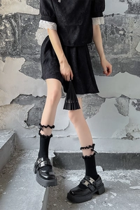 Détail de chaussettes noires à dentelle avec chaussures compensées à boucles métalliques