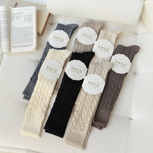 Detail of cable knit wool knee-high socks in black grey and beige with diamond textures