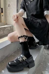 Détail de chaussures Mary Jane noires à boucles et chaussettes à dentelle et nœud