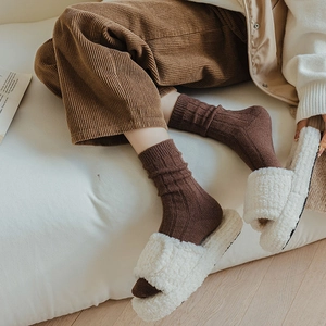 Brown ribbed wool socks paired with white faux fur slippers for a cozy winter look
