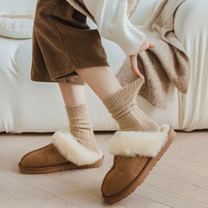 Detail of warm brown suede slippers with white faux fur lining and thick non-slip soles