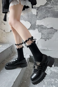 Détail de Mary Janes noires à semelle épaisse avec chaussettes à volants et nœuds