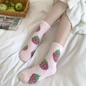 Cozy pink coral fleece strawberry socks displayed in a warm home bedroom setting