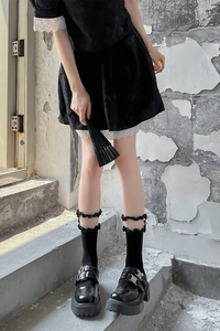 Détail de chaussettes gothiques en dentelle avec chaussures Mary Jane et robe sombre