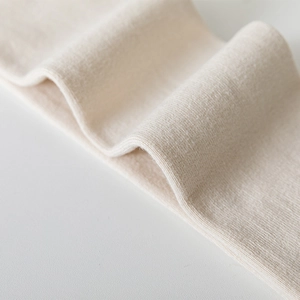 Détail de chaussettes hautes en maille blanc crème montrant la texture et le tissage