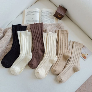 Close-up of thick ribbed wool socks in earth tones on a cozy knit blanket