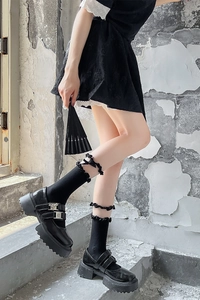 Détail de chaussures Mary Jane noires avec chaussettes en dentelle à volants et nœuds