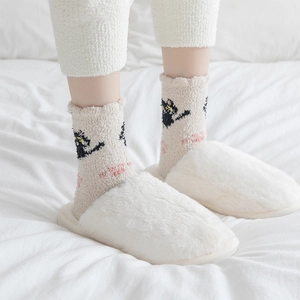 Detailed view of cozy white plush slippers and cute cat pattern coral fleece socks