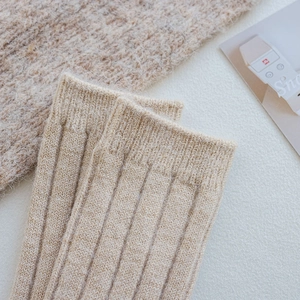 Detail of oat beige wool socks featuring vertical striped knitting and warm texture