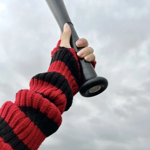 Detail of red and black striped knitted arm warmer with punk aesthetic and fingerless design
