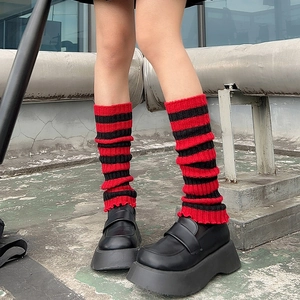 Close-up of red and black striped knitted leg warmers styled with chunky platform shoes