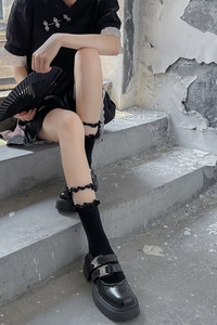 Détail de chaussettes noires à volants portées avec des chaussures Mary Jane à plateformes
