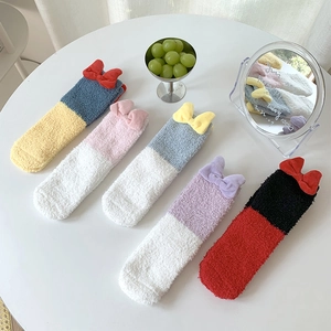 Close-up of fluffy coral fleece winter socks with decorative 3D bows in various colors