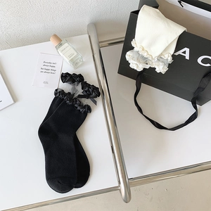 Détails de chaussettes en tulle transparent avec nœuds sur un support chic