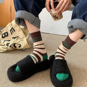 Gestreepte katoenen sokken gecombineerd met zwarte harige pantoffels voor de winterlook