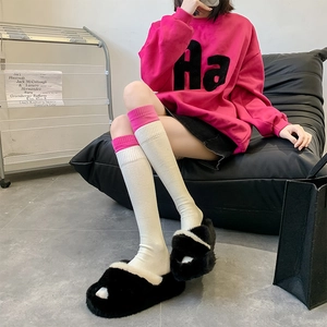 Detailed close-up of pink ribbed cuffs on cream knitted knee-high socks for women