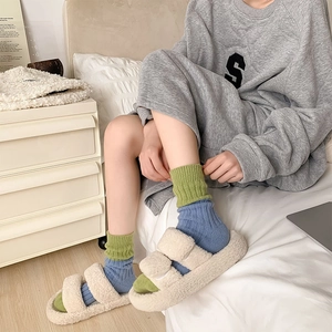 Detail of cream plush slippers featuring thick soles and double buckle strap texture