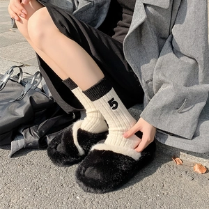 Detailed shot of black and white plush slippers and striped socks with number 5 embroidery
