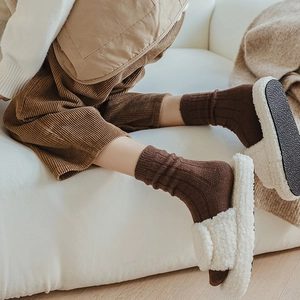 Detail of wool socks and faux fur slippers on feet for warm winter home comfort