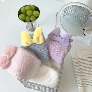 Cozy coral fleece socks with 3D bows in pink, blue, and purple displayed in a basket