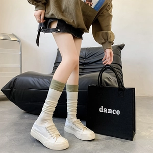 Close-up of white knitted knee-high socks with olive green trim and thick canvas shoes