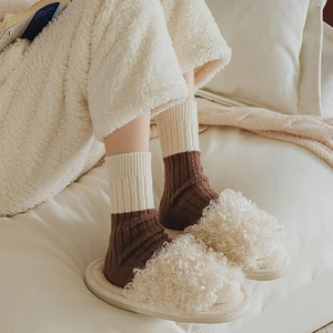 Close-up of winter wool ribbed socks paired with white faux fur open-toe slippers