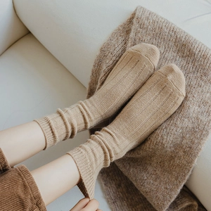 Close-up of beige ribbed wool socks texture worn in a cozy indoor setting